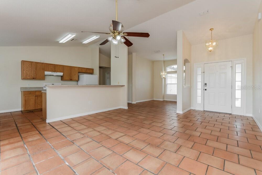 An open-concept living area features terracotta tile flooring, a kitchen breakfast bar, and vaulted ceilings — 1001 GARY DRIVE, ST CLOUD, FL