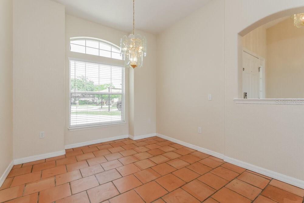 An empty dining area features terracotta tile flooring, a chandelier, and a large arched window — 1001 GARY DRIVE, ST CLOUD, FL