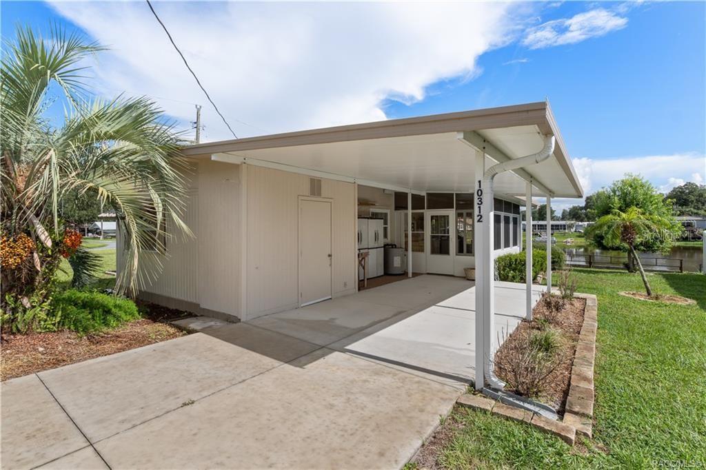 A concrete driveway leads to a covered carport attached to a light-colored mobile home — 10312 E PIKE DRIVE, INVERNESS, FL