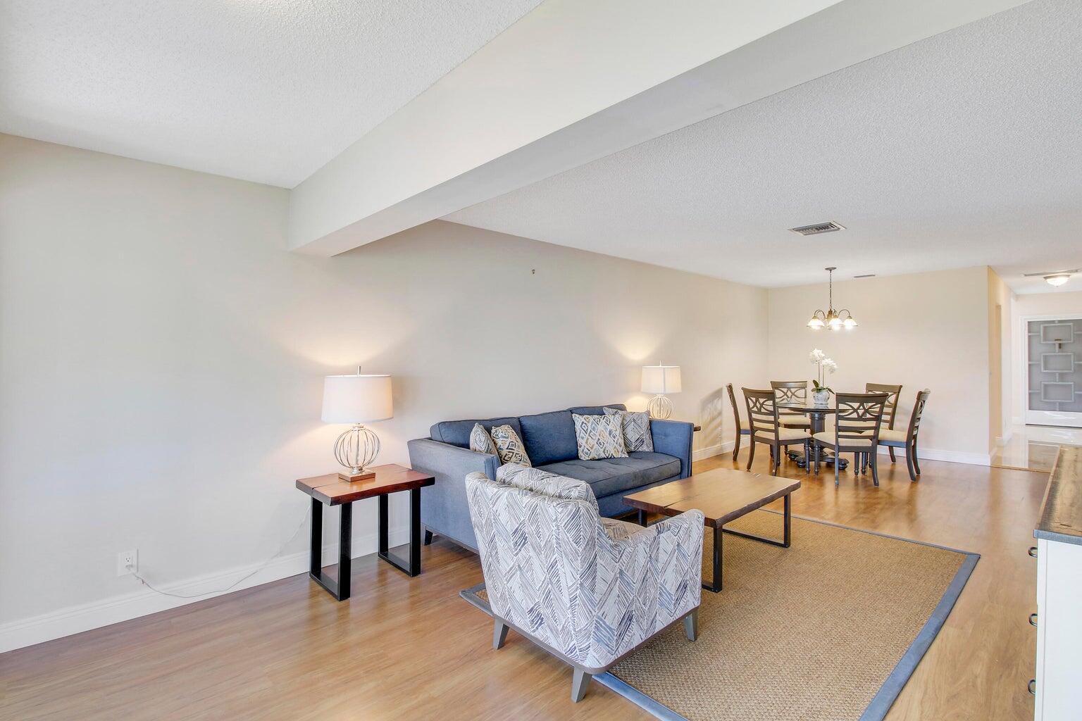 A living room with wood flooring, a blue sofa, and an adjacent dining area — 2730 SW 13th Street # 203, Delray Beach FL 33445, DELRAY BEACH, FL