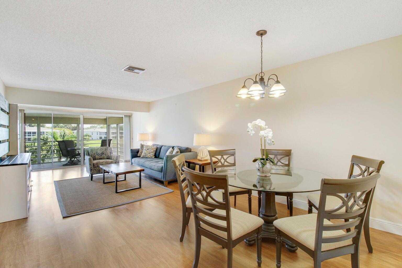 A living and dining area with wood floors, a glass table, and a blue sofa — 2730 SW 13th Street # 203, Delray Beach FL 33445, DELRAY BEACH, FL