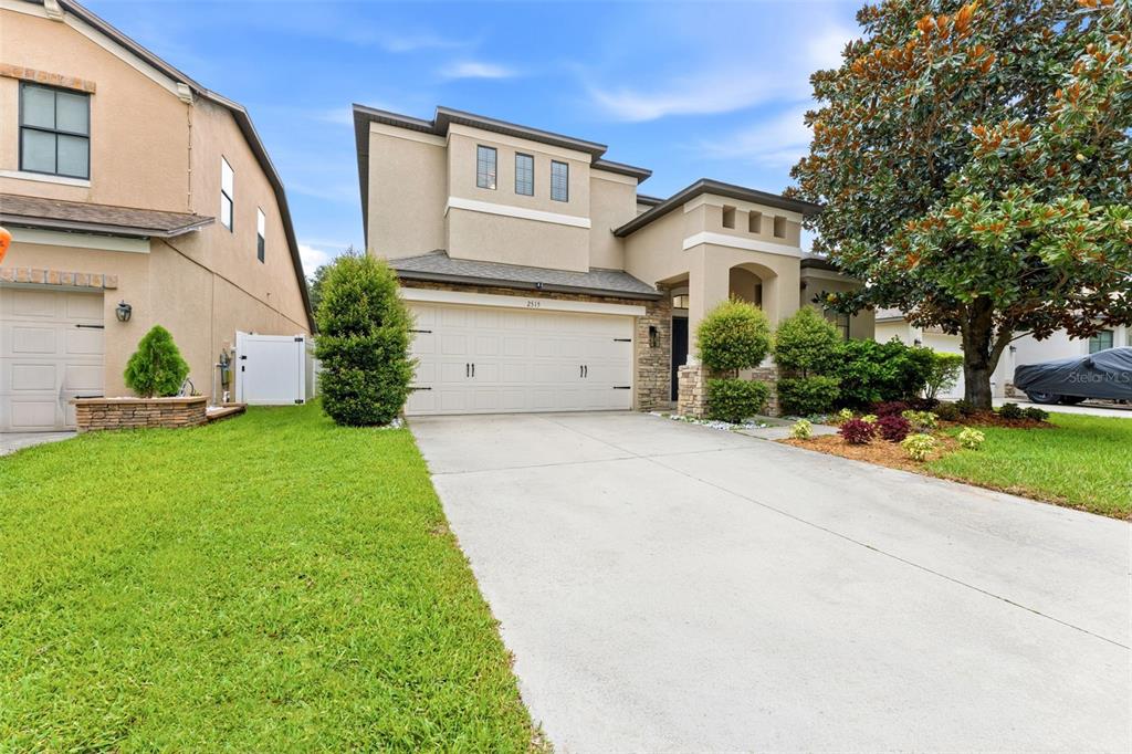A two-story suburban house with a beige stucco exterior, stone accents, and a concrete driveway — 2515 CROSS MORE STREET, VALRICO, FL