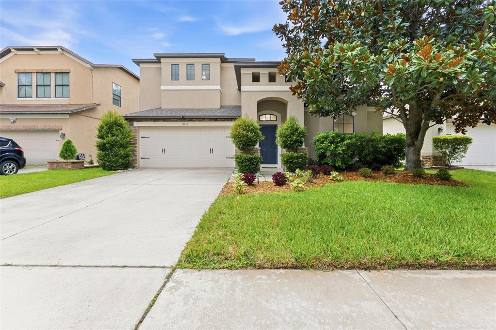 A two-story suburban house with a beige stucco exterior, a garage, and a front lawn — 2515 CROSS MORE STREET, VALRICO, FL