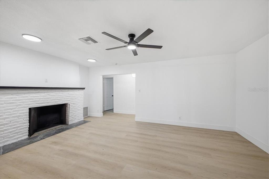 A living room features white walls, light wood-look flooring, and a white brick fireplace — 3308 3RD AVENUE W, BRADENTON, FL