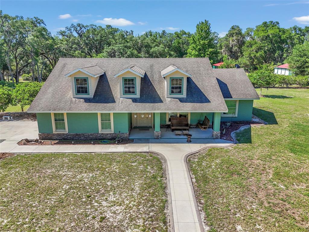 A green two-story house with a front porch, three dormers, and a concrete walkway — 3325 S HWY 314A, OCKLAWAHA, FL