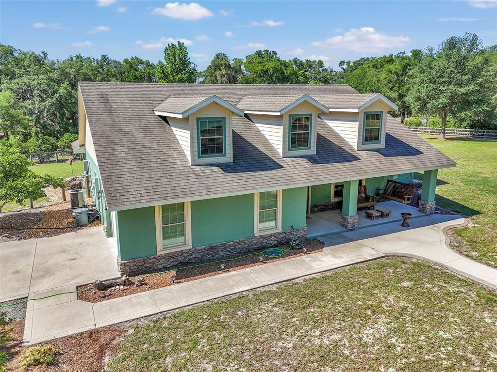 An aerial view shows a green house with a stone base and three dormer windows — 3325 S HWY 314A, OCKLAWAHA, FL