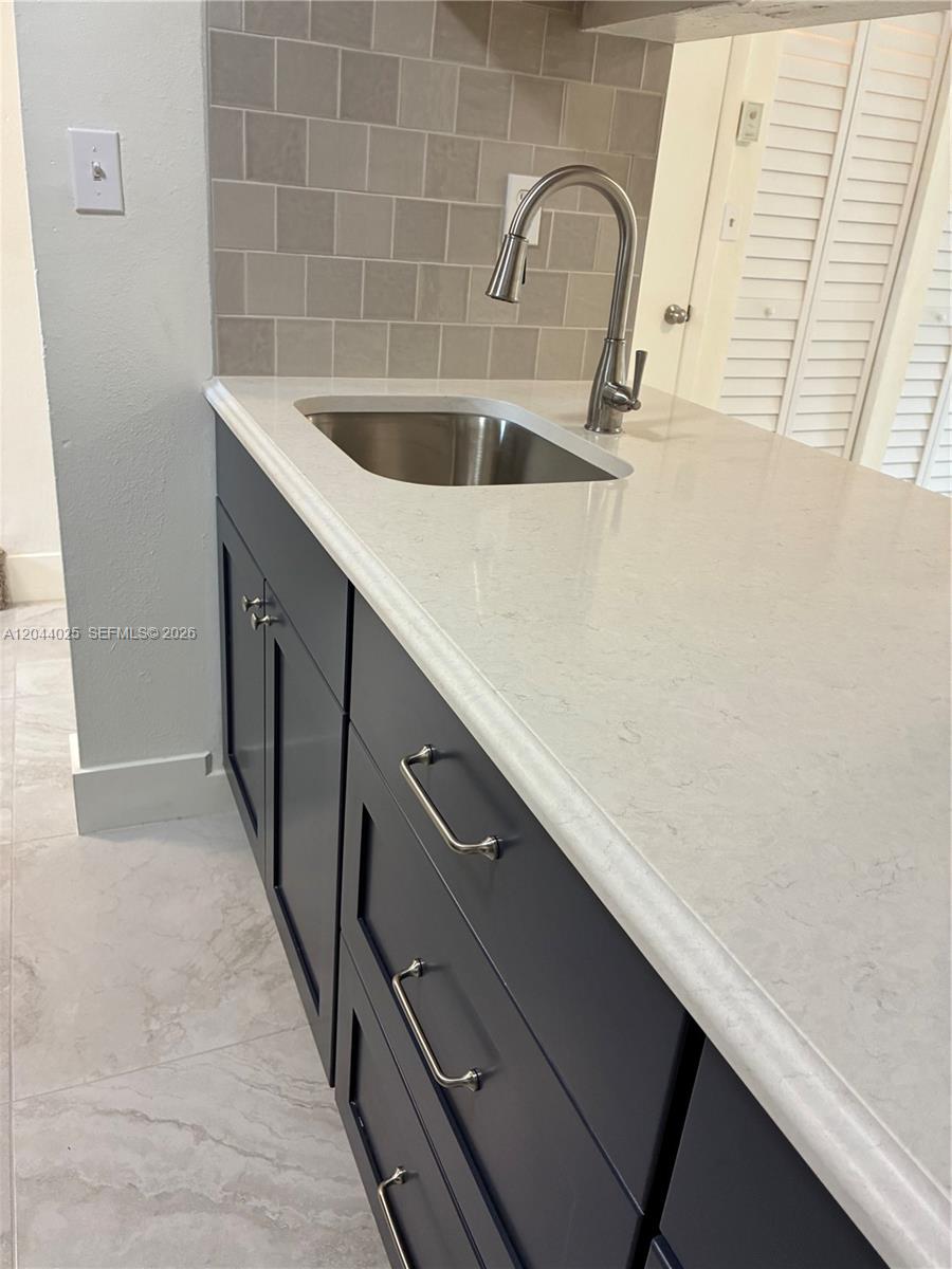 A kitchen features dark blue cabinets, a white quartz countertop, and a stainless steel sink — 153 NE 141st St # B, Miami FL 33161, MIAMI, FL