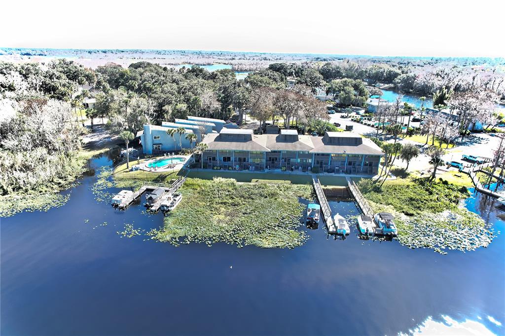 An aerial view shows a multi-story waterfront building with a swimming pool and boat docks — 2329 RIVER RIDGE ROAD UNIT 13, DELAND, FL