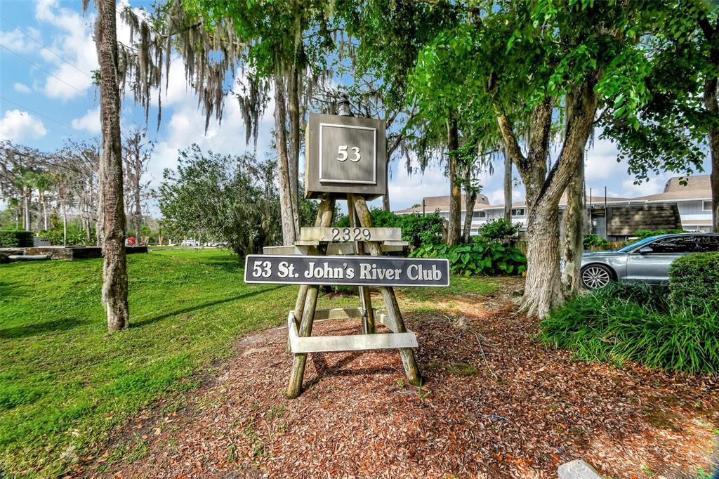 A wooden sign for St. John's River Club stands in a grassy, tree-filled outdoor area — 2329 RIVER RIDGE ROAD UNIT 13, DELAND, FL