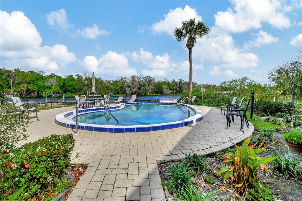 An outdoor swimming pool with a blue tile border sits on a paved patio — 2329 RIVER RIDGE ROAD UNIT 13, DELAND, FL