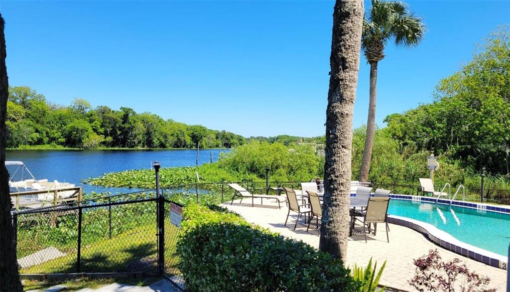 A swimming pool and patio overlook a river with a boat docked nearby — 2329 RIVER RIDGE ROAD UNIT 13, DELAND, FL