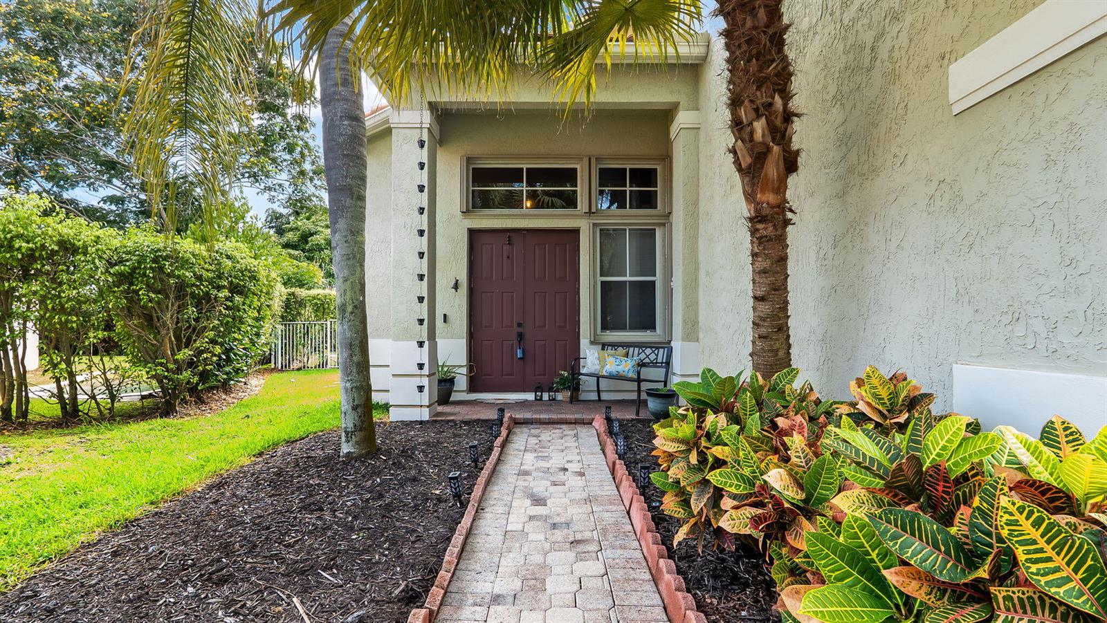 A paved walkway leads to the front entrance of a house with a brown door — 4411 Stone Ridge Way, Weston FL 33331, WESTON, FL