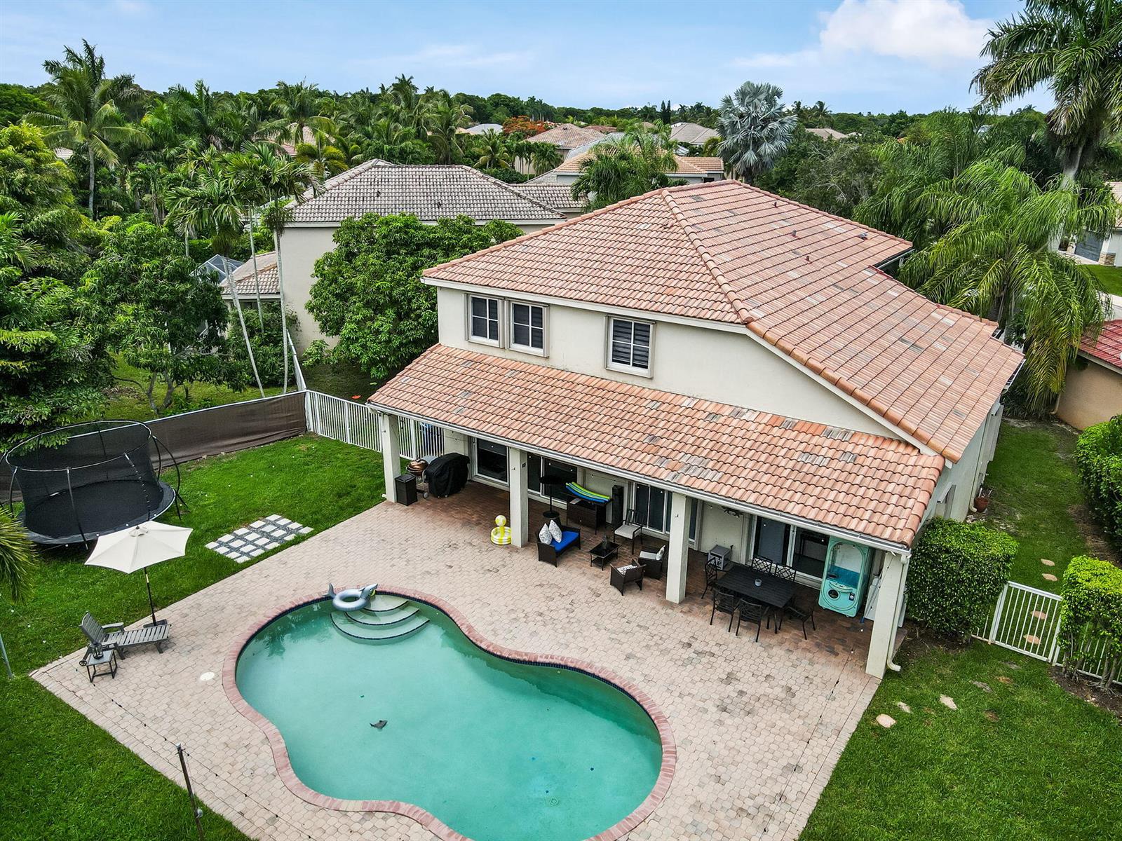 An aerial view of a two-story house with a backyard pool, patio, and trampoline — 4411 Stone Ridge Way, Weston FL 33331, WESTON, FL