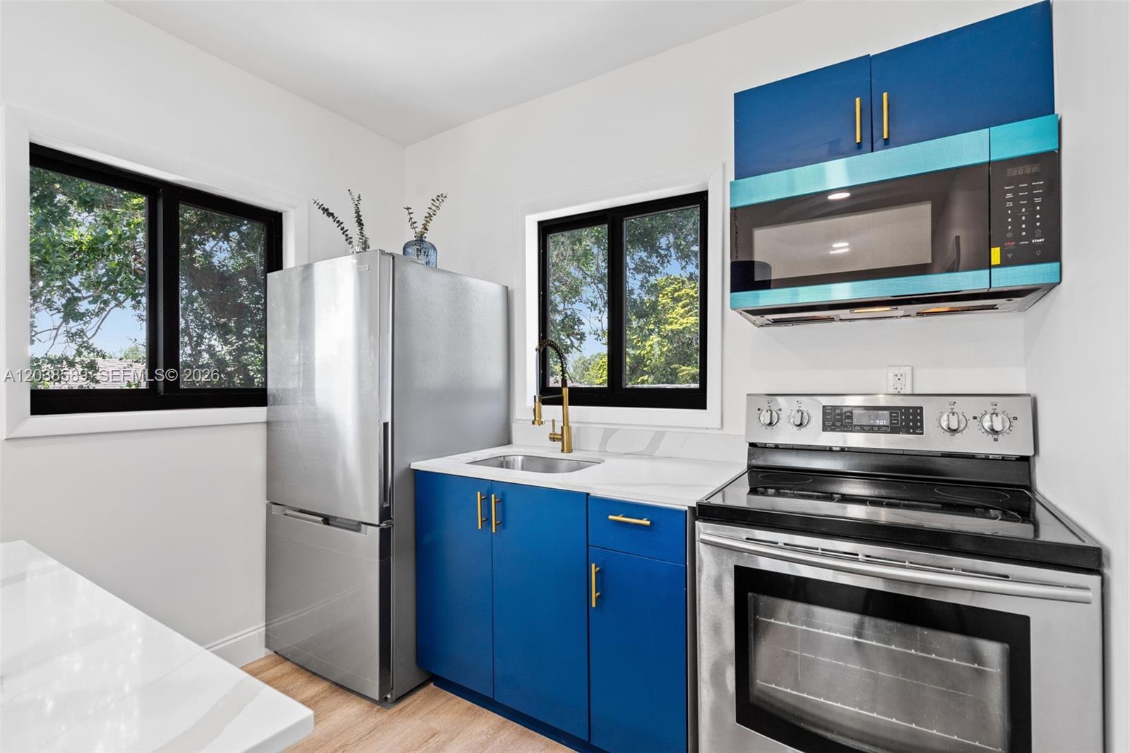 A kitchen features blue cabinets, gold hardware, stainless steel appliances, and white countertops — 1824 NW 47th St # A, Miami FL 33142, MIAMI, FL