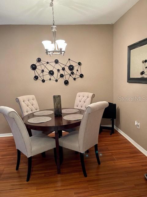 A dining area features a round wooden table, four upholstered chairs, and a metal wall sculpture — 1507 LEGACY CLUB DRIVE UNIT 1507, MAITLAND, FL