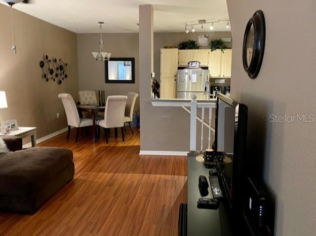 A living room with wood-look flooring opens to a dining area and kitchen — 1507 LEGACY CLUB DRIVE UNIT 1507, MAITLAND, FL