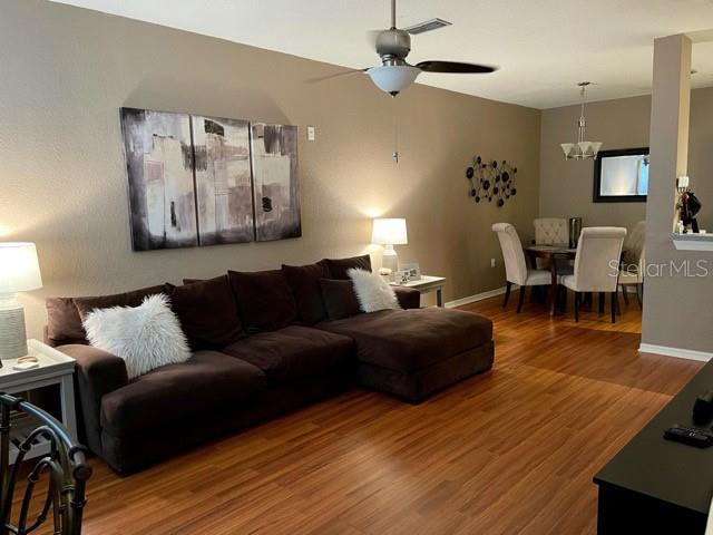 A living room with a brown sectional sofa, wood flooring, and an adjacent dining area — 1507 LEGACY CLUB DRIVE UNIT 1507, MAITLAND, FL