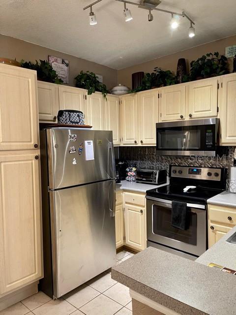 A kitchen features light-colored cabinets, stainless steel appliances, and a tiled backsplash — 1507 LEGACY CLUB DRIVE UNIT 1507, MAITLAND, FL