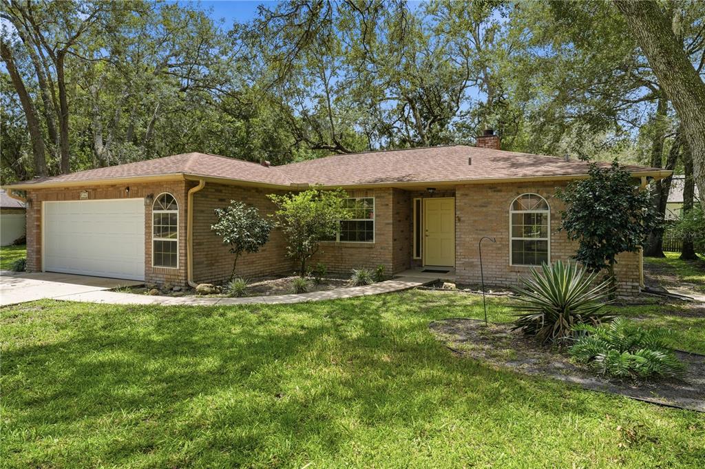 A single-story brick house with a two-car garage, arched windows, and a yellow front door — 1356 6TH STREET, ORANGE CITY, FL