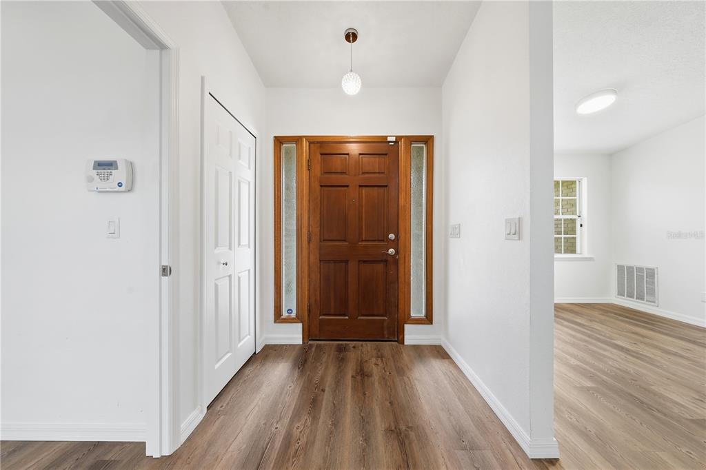 An entryway features a wood front door with sidelights, white walls, and wood-look flooring — 1356 6TH STREET, ORANGE CITY, FL
