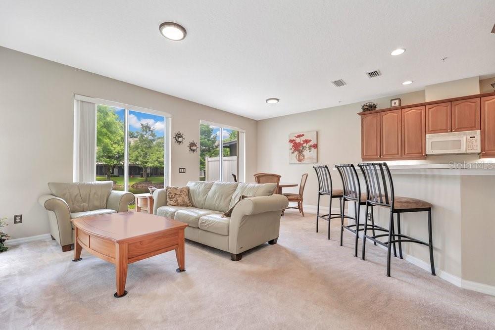 A living room with beige carpet, a light-colored sofa, and a breakfast bar with stools — 617 PINEBRANCH CIRCLE, WINTER SPRINGS, FL