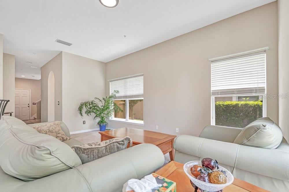 A living room features light-colored leather sofas, a wooden coffee table, and two large windows — 617 PINEBRANCH CIRCLE, WINTER SPRINGS, FL