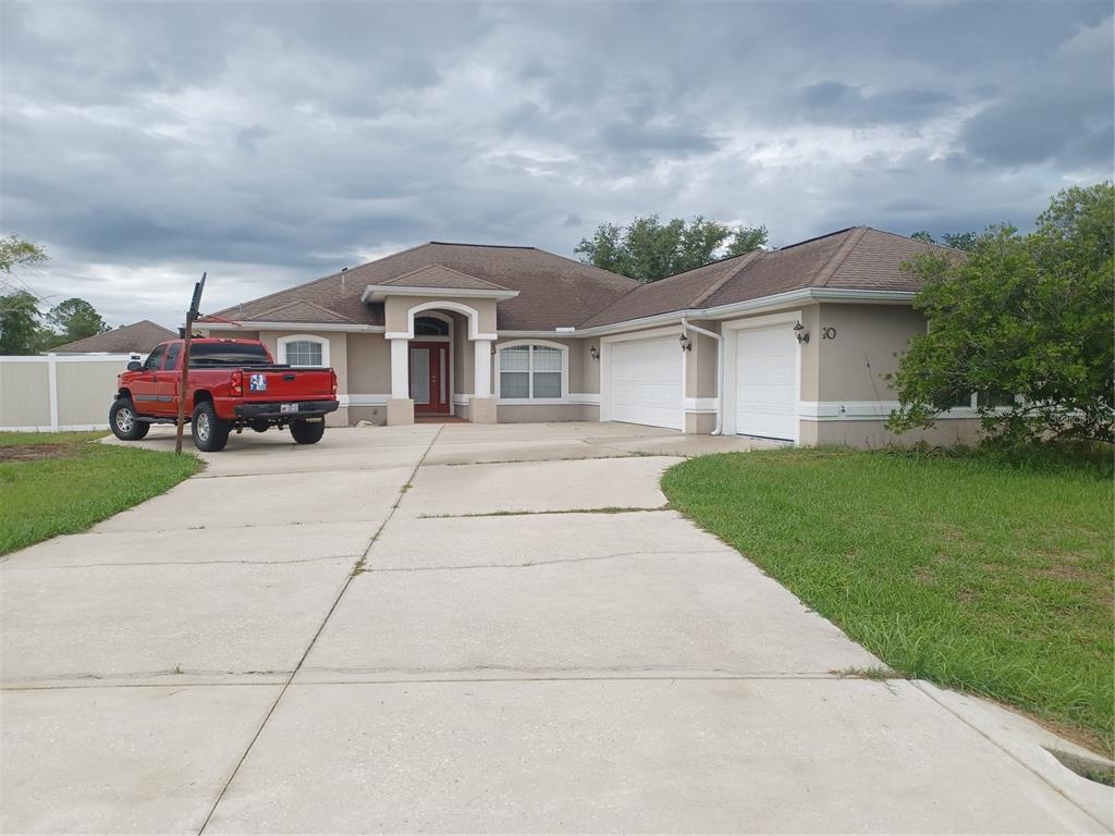 A single-story house with a beige exterior, brown roof, and a three-car garage — 10 ROCKEFELLER DRIVE, PALM COAST, FL