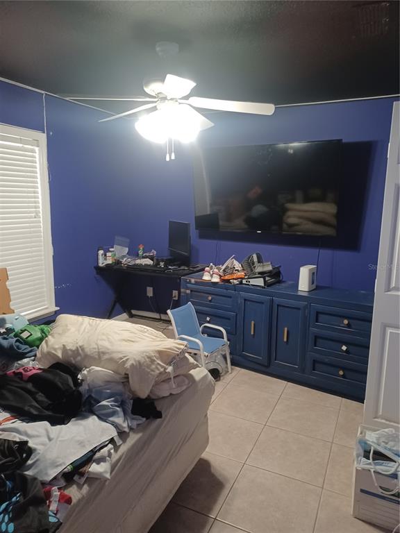 A bedroom features blue walls, a ceiling fan, a large television, and a blue dresser — 10 ROCKEFELLER DRIVE, PALM COAST, FL