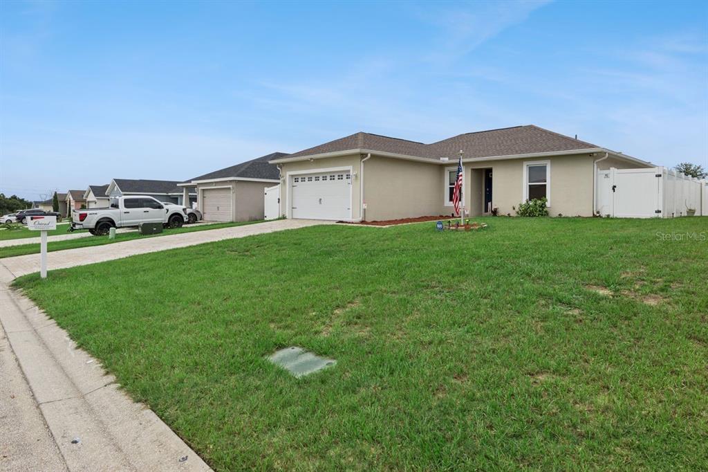 A single-story suburban house with a tan exterior, a two-car garage, and a front lawn — 313 SUMMIT AVENUE, LAKE WALES, FL