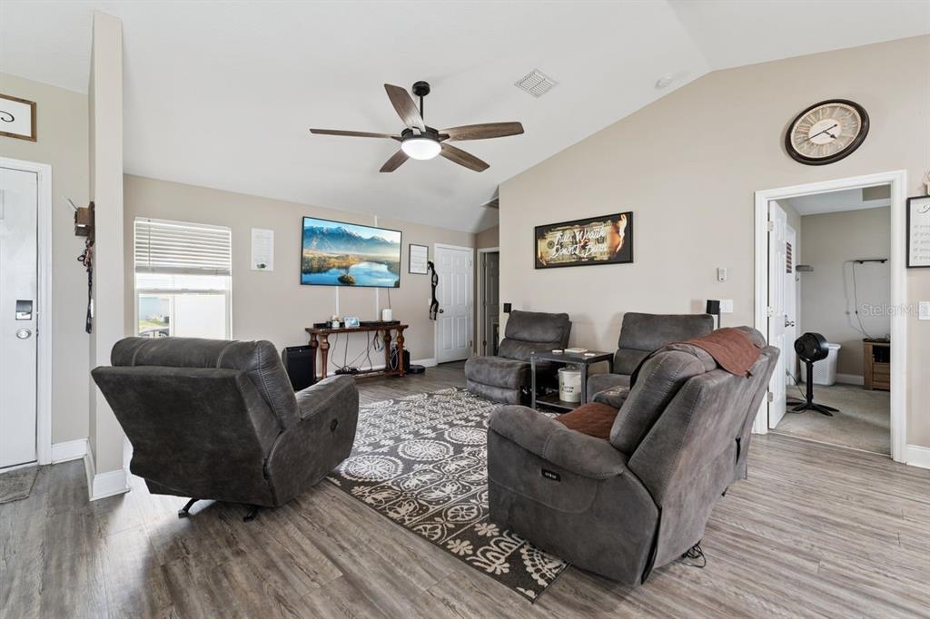 A living room features gray reclining chairs, a patterned area rug, and a wall-mounted television — 313 SUMMIT AVENUE, LAKE WALES, FL