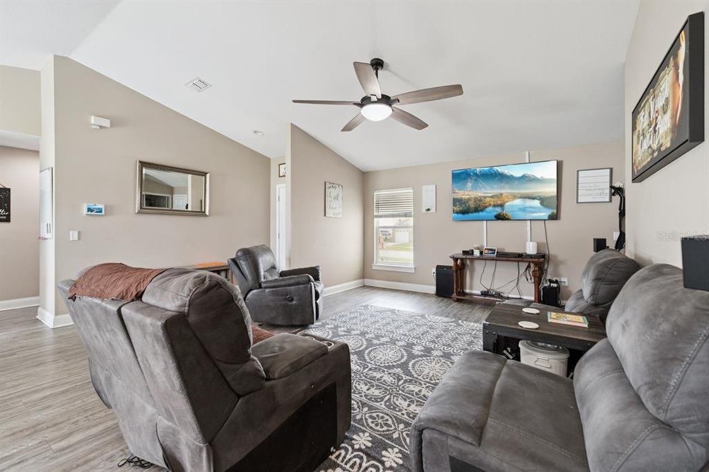 A living room features gray reclining furniture, a patterned area rug, and a wall-mounted television — 313 SUMMIT AVENUE, LAKE WALES, FL