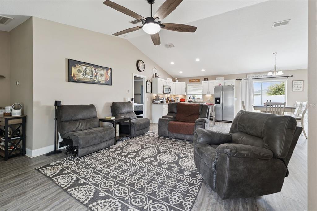 A living room with gray recliners, a patterned area rug, and an open-concept kitchen — 313 SUMMIT AVENUE, LAKE WALES, FL