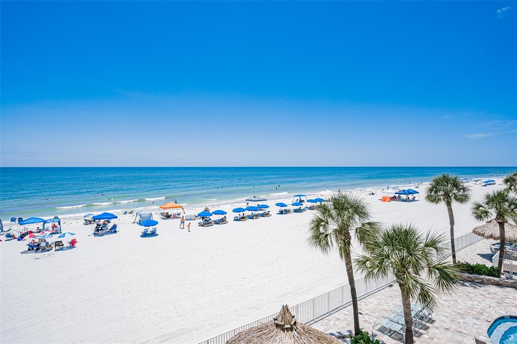 An elevated view of a white sand beach with blue umbrellas and palm trees — 17200 GULF BOULEVARD UNIT 202, NORTH REDINGTON BEACH, FL