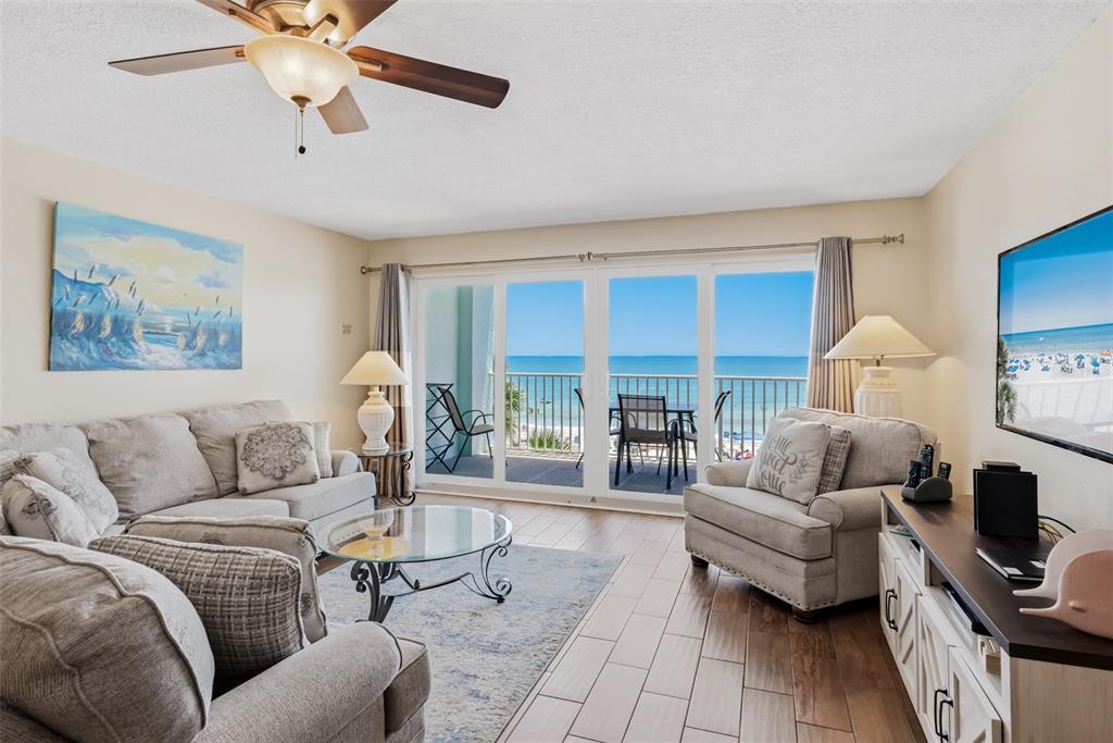 A living room with light-colored furniture, a glass coffee table, and a balcony overlooking the ocean — 17200 GULF BOULEVARD UNIT 202, NORTH REDINGTON BEACH, FL