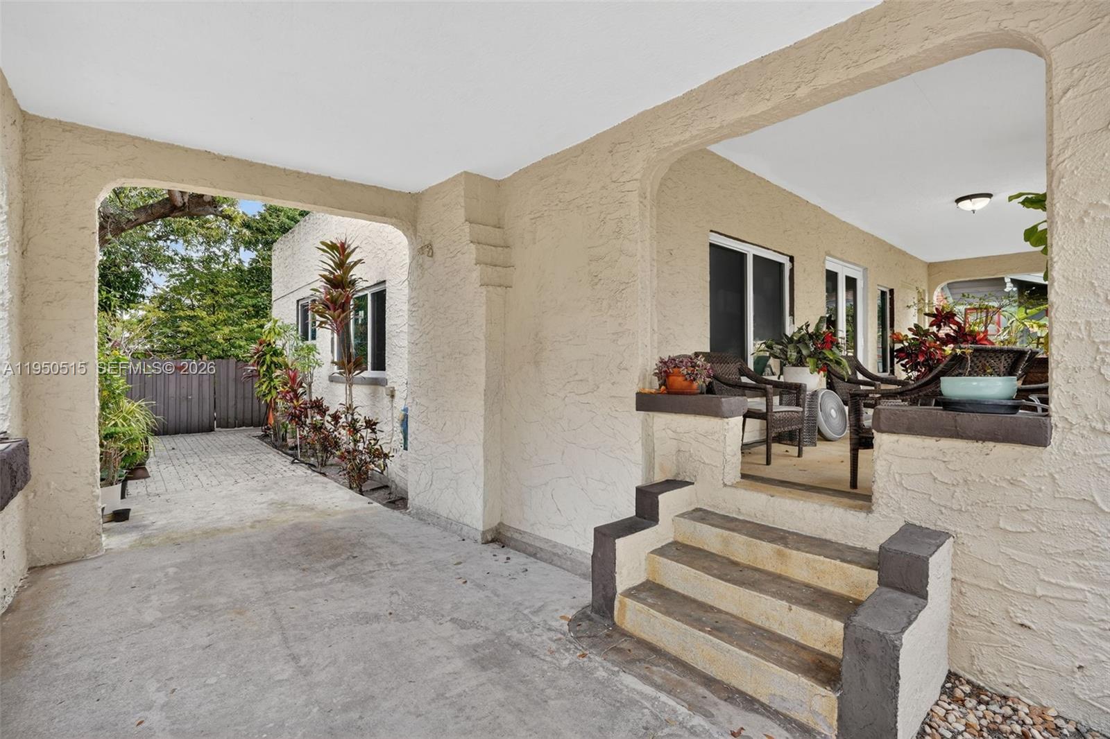 A beige stucco house features a covered front porch with steps and a side driveway — 1649 SW 11th Ter, Miami FL 33135, MIAMI, FL