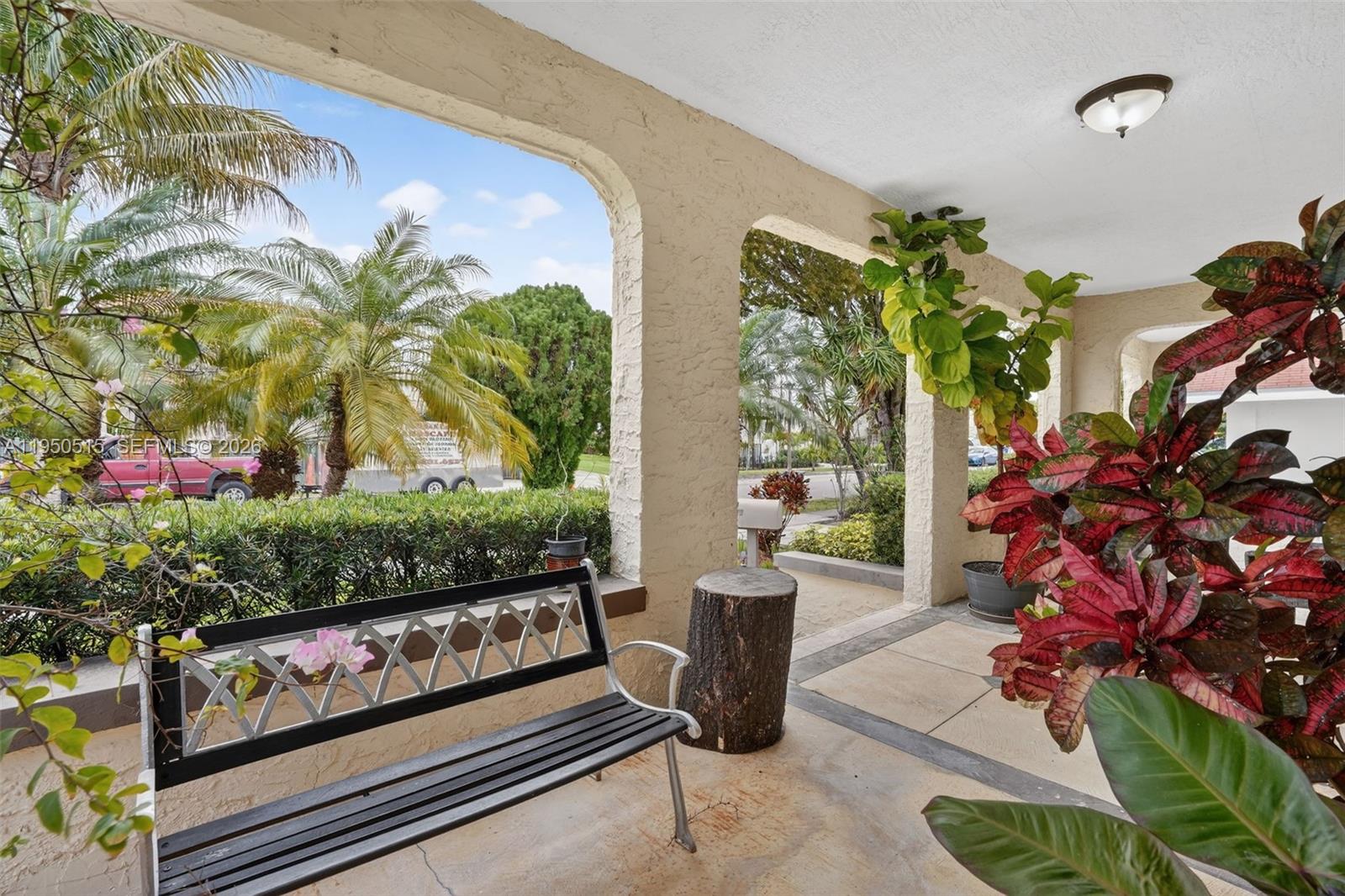 A covered porch features a metal bench, a tree stump, and potted plants — 1649 SW 11th Ter, Miami FL 33135, MIAMI, FL
