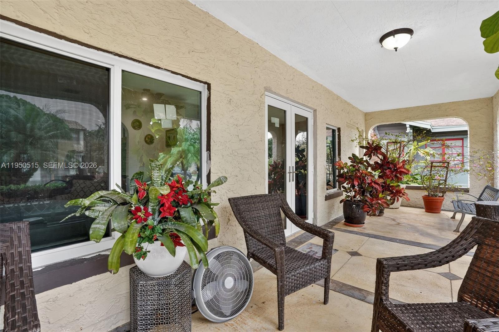 A covered outdoor patio features wicker chairs, potted plants, and a portable fan — 1649 SW 11th Ter, Miami FL 33135, MIAMI, FL