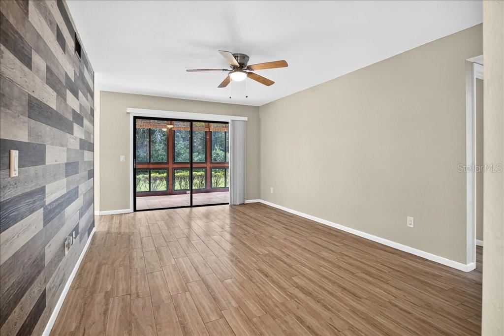A living room features wood-look tile flooring, a wood-plank accent wall, and sliding glass doors — 15 SHERBURY COURT, PALM COAST, FL