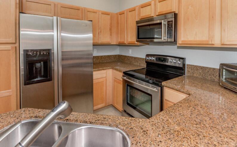 A kitchen features stainless steel appliances, light wood cabinets, and speckled granite countertops — 3019 Laurel Ridge Circle, Riviera Beach FL 33404, RIVIERA BEACH, FL