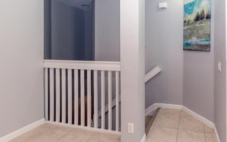 A tiled landing area features a white wooden railing overlooking a staircase — 3019 Laurel Ridge Circle, Riviera Beach FL 33404, RIVIERA BEACH, FL
