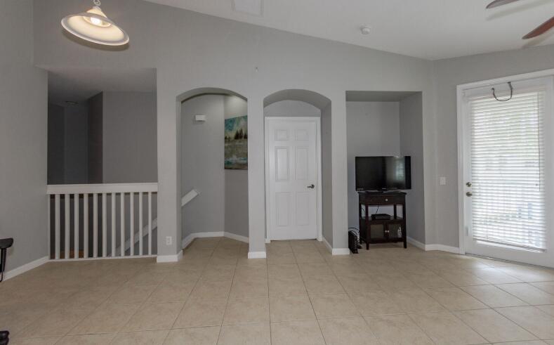 A room with light gray walls, tile flooring, arched doorways, a white door, and a television — 3019 Laurel Ridge Circle, Riviera Beach FL 33404, RIVIERA BEACH, FL