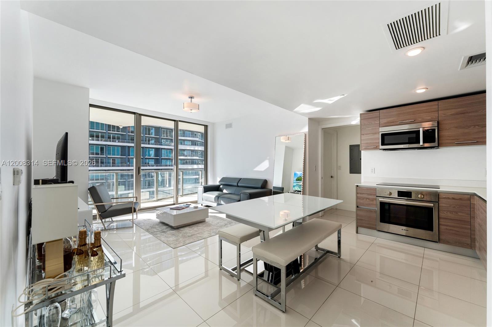 A modern open-concept living area features a kitchen, dining table, and balcony with city views — 1300 S Miami Ave # 2907, Miami FL 33130, MIAMI, FL
