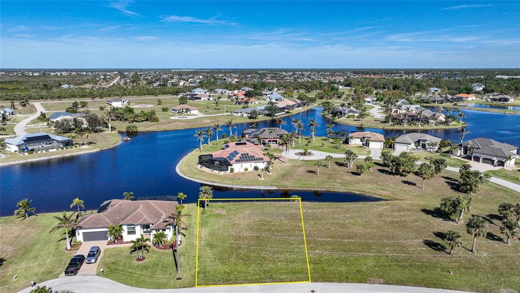 An aerial view shows a vacant residential lot outlined in yellow next to a house — 17146 ANTHEM LANE, PUNTA GORDA, FL