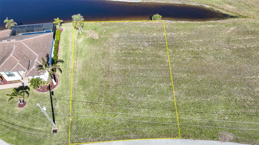 An aerial view shows a vacant, rectangular residential lot bordered by a house and water — 17146 ANTHEM LANE, PUNTA GORDA, FL