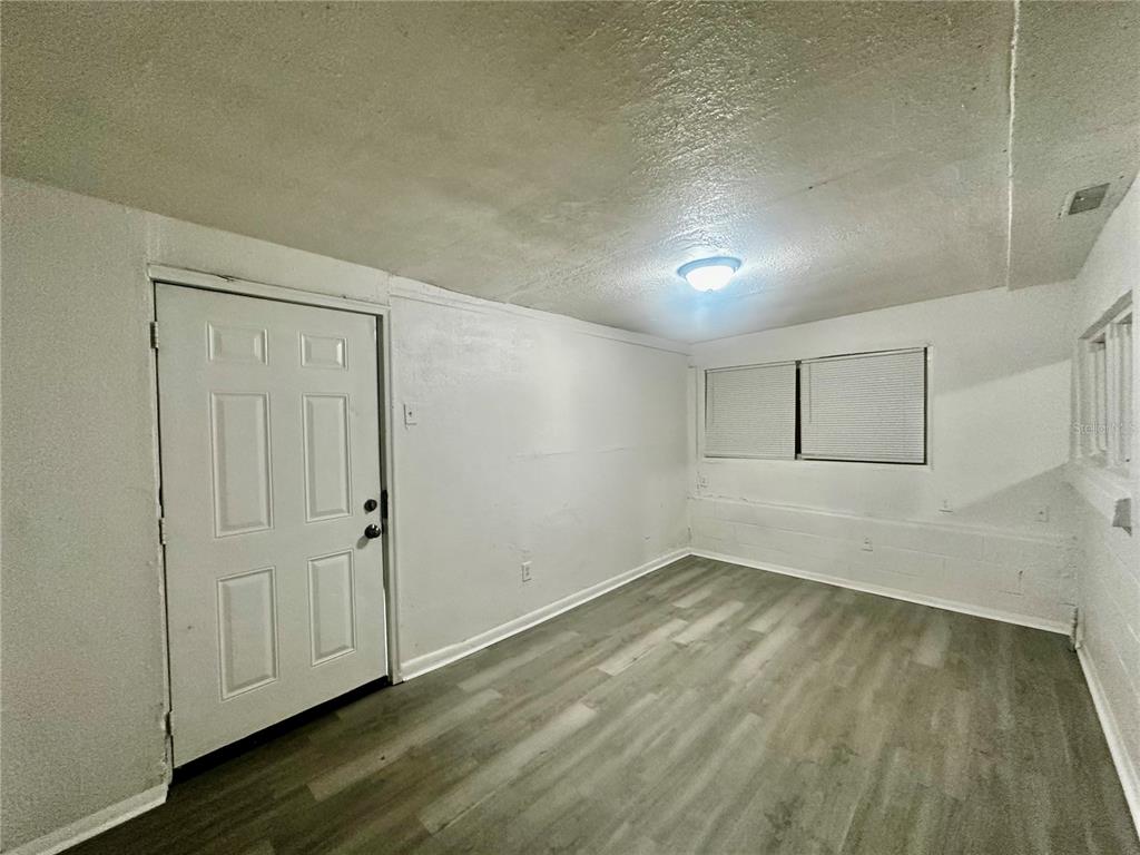 A room with white walls, a white door, a window with blinds, and wood-look flooring — 1907 S RIO GRANDE AVENUE, ORLANDO, FL