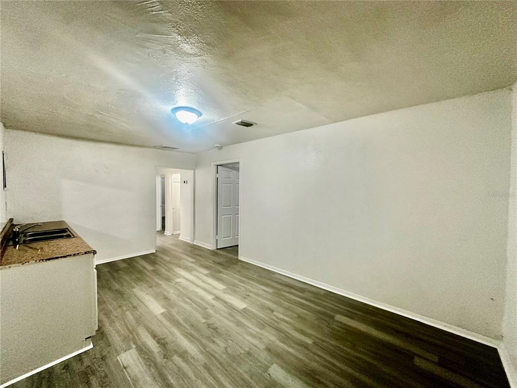 A kitchen area with wood-look flooring, white walls, and a granite countertop — 1907 S RIO GRANDE AVENUE, ORLANDO, FL