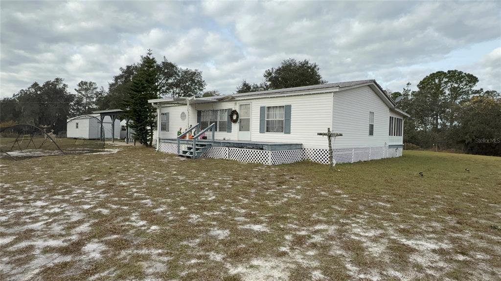 A white mobile home with a front deck and lattice skirting sits on a grassy lot — 29605 FULLERVILLE ROAD, DELAND, FL