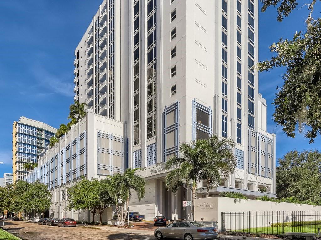 A tall, modern white high-rise apartment building with a parking garage base and palm trees — 415 E PINE STREET UNIT PH, ORLANDO, FL