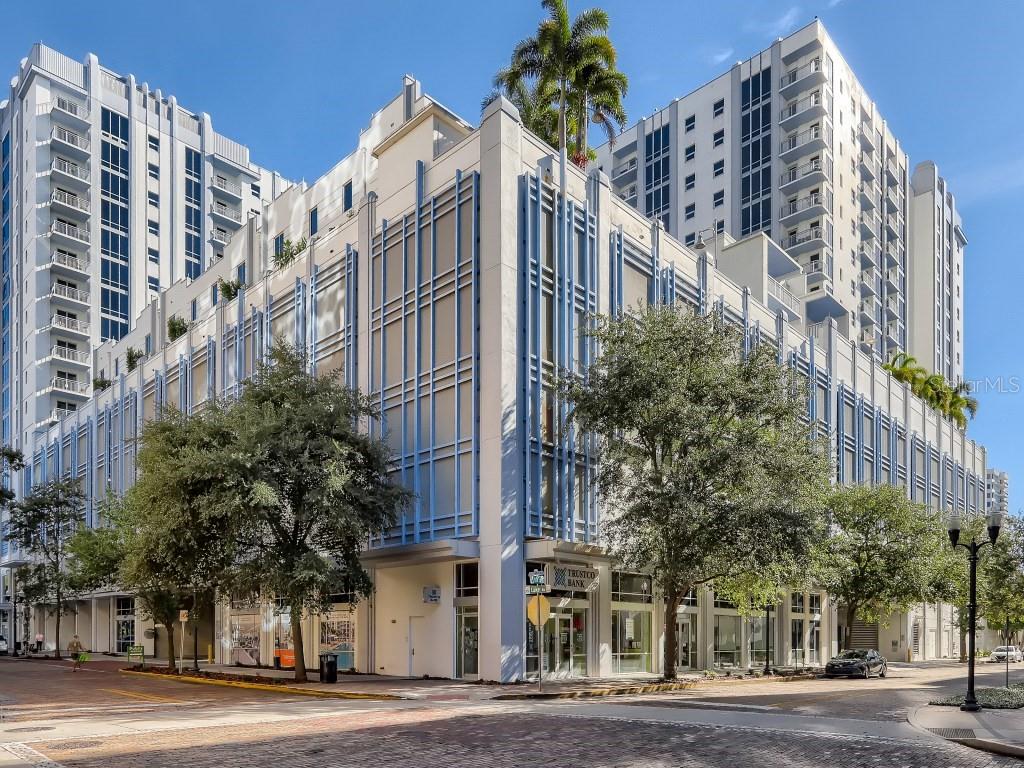 A multi-story building with a light-colored facade and blue accents stands on a brick street — 415 E PINE STREET UNIT PH, ORLANDO, FL