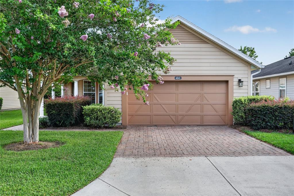 A single-story house with beige siding, a two-car garage, and a paver driveway — 4845 NW 35TH LANE ROAD, OCALA, FL